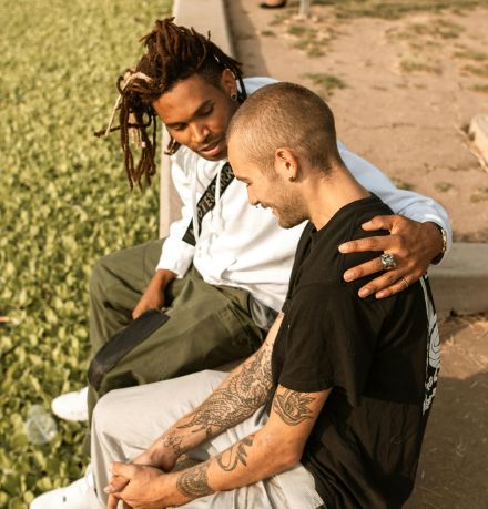 Two friends share a supportive moment outdoors, highlighting affection and companionship.