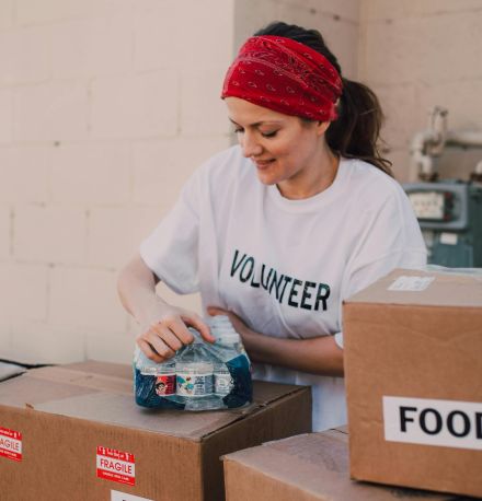 Volunteer packing food and water for charity at an outdoor event, emphasizing community support.